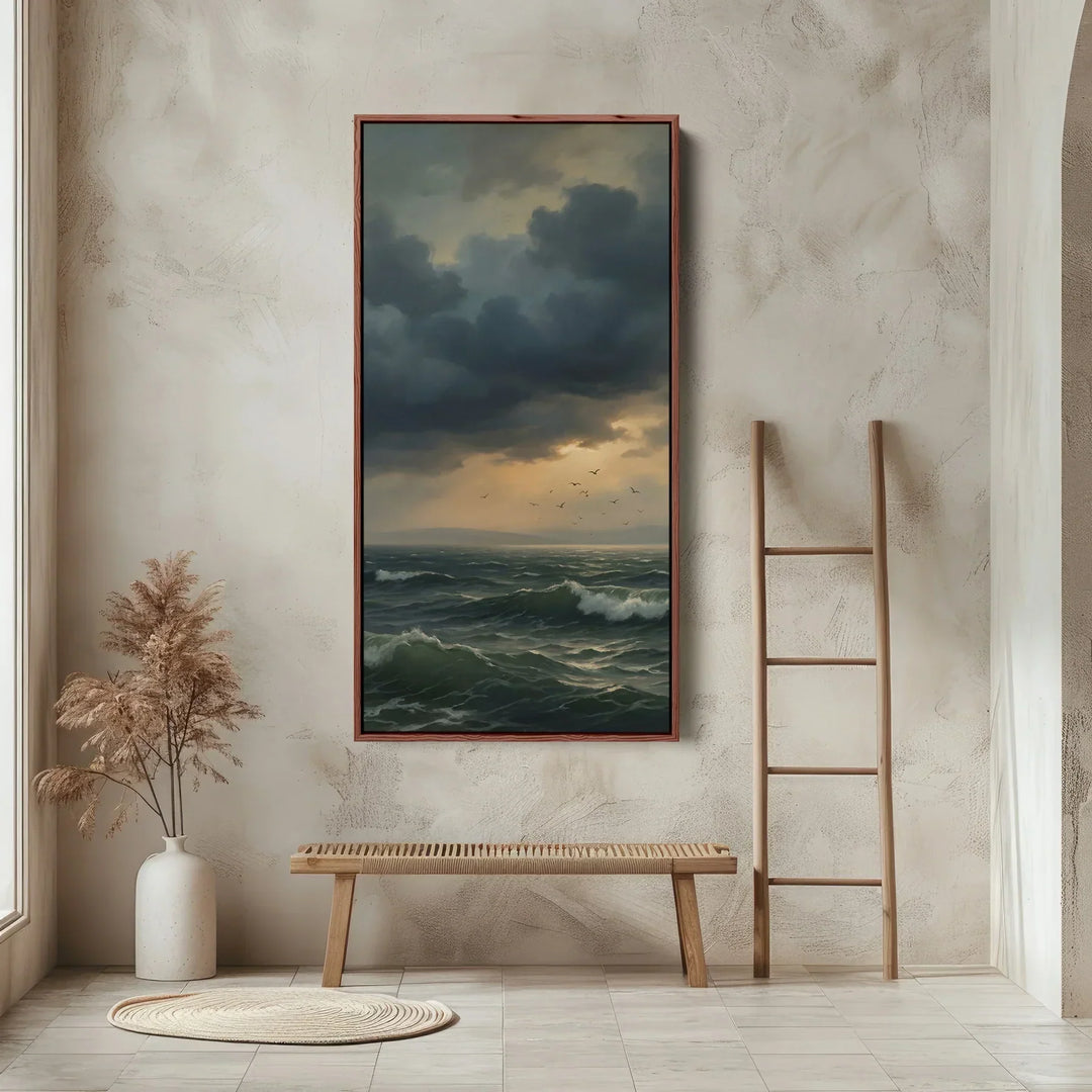  Large framed coastal artwork depicting dramatic storm clouds gathering over a turbulent sea with crashing waves, styled above a natural oak slatted bench in a minimalist entryway. 